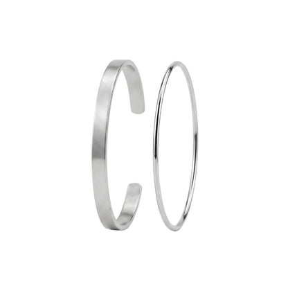 Two minimalist silver metal bangles, one with a matte finish and one with a polished reflective finish, standing upright against a clean white background.